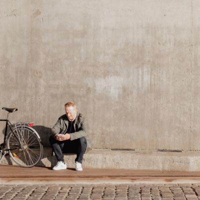 Mand ved grå bygning med sin cykel
